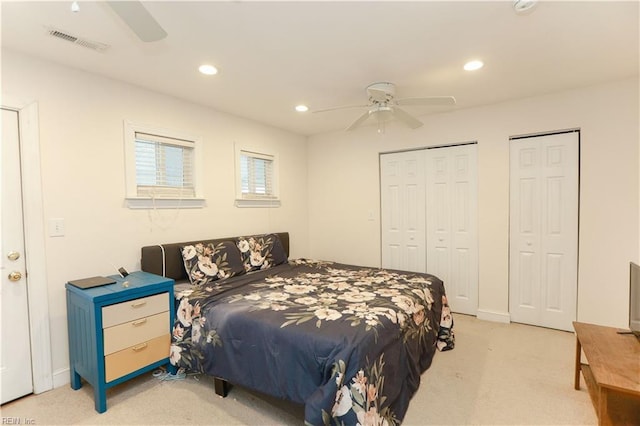 bedroom with two closets, light colored carpet, and ceiling fan