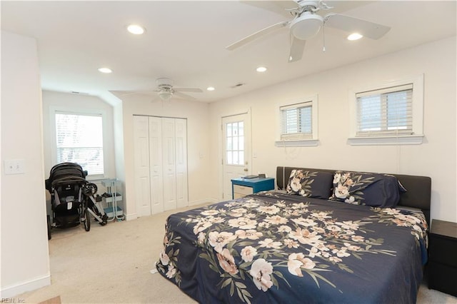 bedroom with multiple windows, light colored carpet, ceiling fan, and a closet