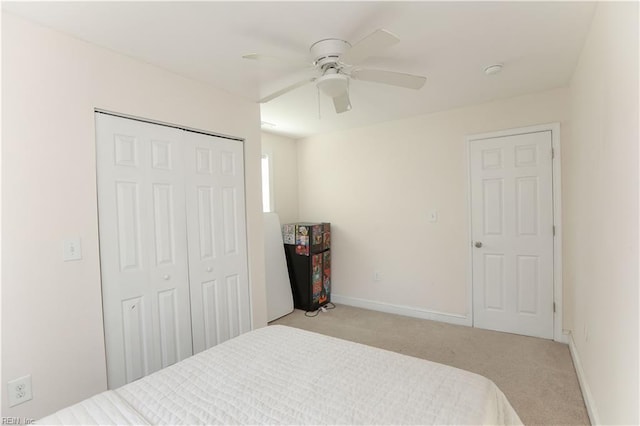 bedroom with ceiling fan, light colored carpet, and a closet