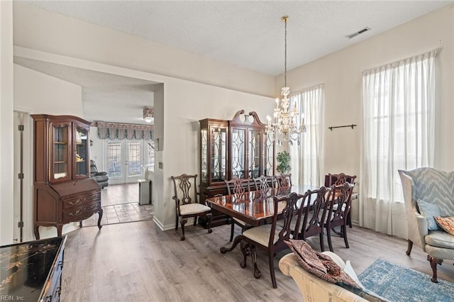 dining room with hardwood / wood-style floors, a textured ceiling, and a chandelier