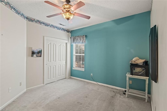 bedroom with ceiling fan, light colored carpet, a textured ceiling, and a closet