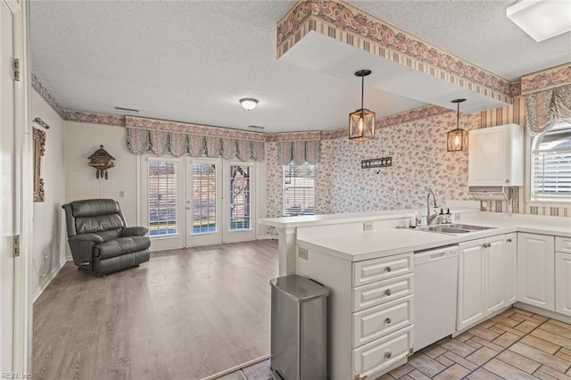 kitchen featuring sink, white cabinetry, a textured ceiling, dishwasher, and kitchen peninsula