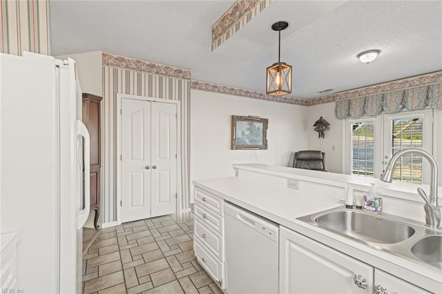 kitchen featuring pendant lighting, sink, white cabinets, white appliances, and a textured ceiling