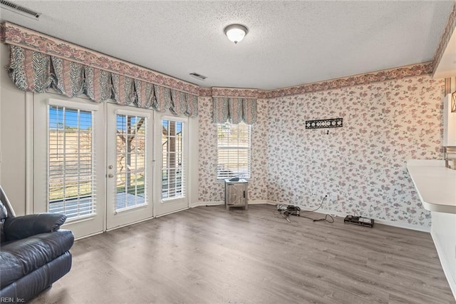 interior space featuring wood-type flooring, french doors, and a textured ceiling