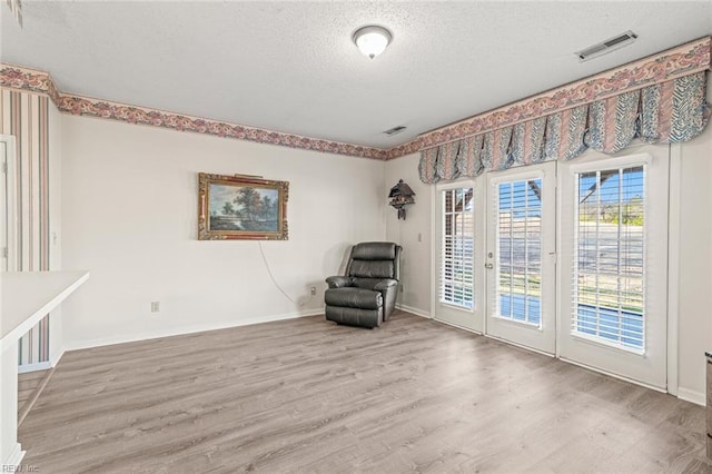 unfurnished room featuring wood-type flooring, a textured ceiling, and french doors