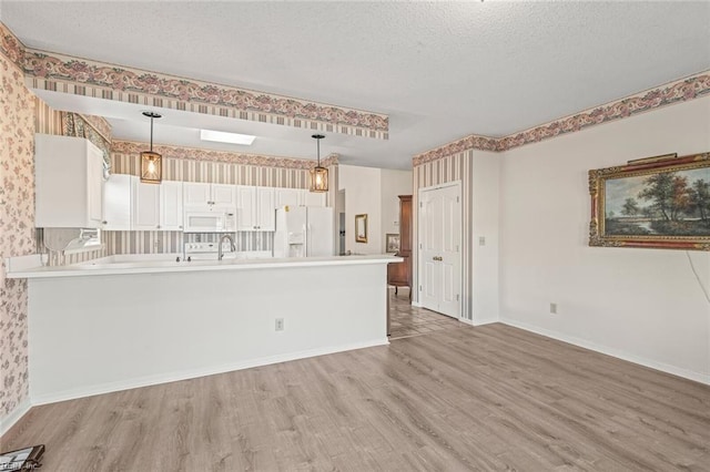 kitchen featuring hanging light fixtures, white cabinetry, white appliances, and light hardwood / wood-style flooring