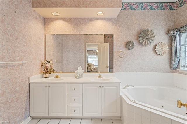 bathroom featuring tiled tub, vanity, and tile patterned flooring