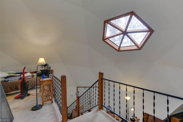 stairs with lofted ceiling with skylight and carpet floors