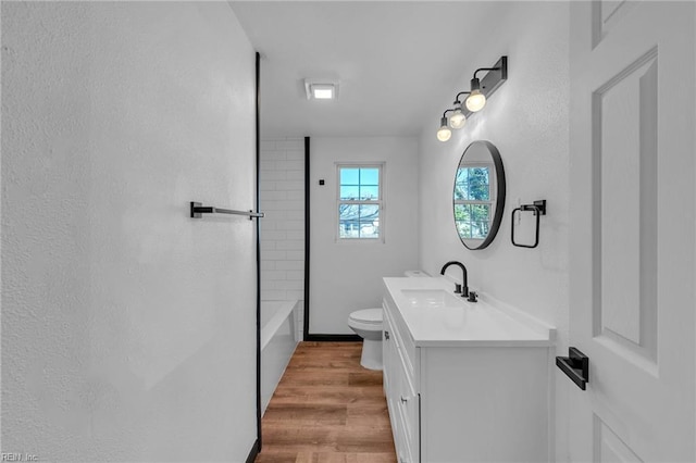 full bathroom with vanity, wood-type flooring, toilet, and tiled shower / bath