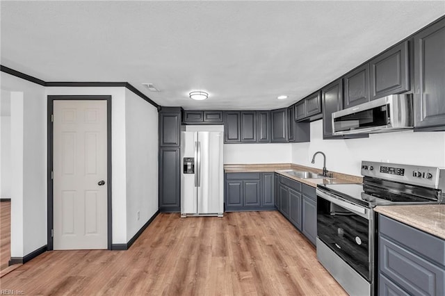 kitchen with appliances with stainless steel finishes, sink, gray cabinetry, ornamental molding, and light hardwood / wood-style floors