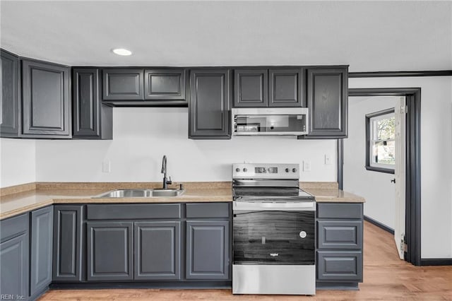 kitchen with stainless steel appliances, sink, gray cabinets, and light hardwood / wood-style flooring