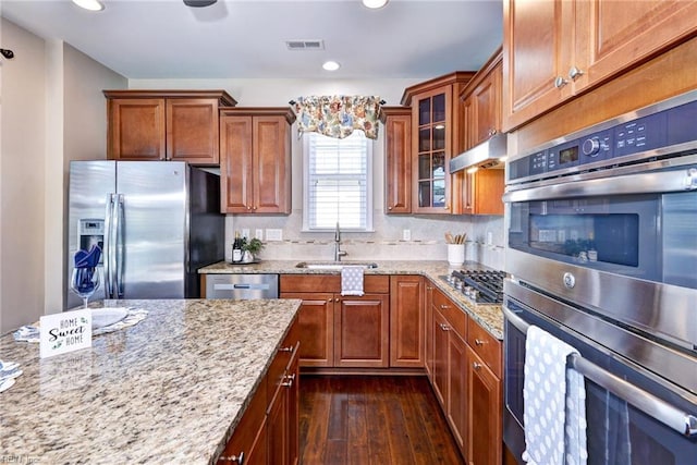 kitchen with stainless steel appliances, light stone countertops, sink, and dark hardwood / wood-style flooring