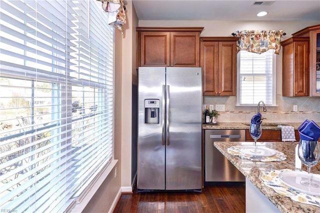 kitchen featuring light stone countertops, appliances with stainless steel finishes, dark wood-type flooring, and backsplash