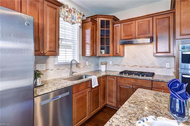 kitchen with sink, light stone counters, appliances with stainless steel finishes, dark hardwood / wood-style flooring, and backsplash