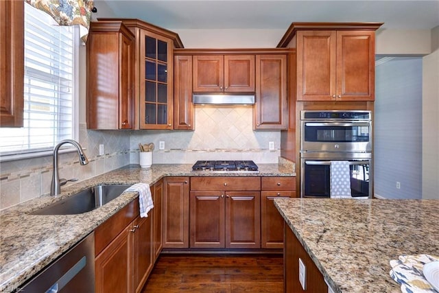 kitchen with tasteful backsplash, sink, dark hardwood / wood-style flooring, stainless steel appliances, and light stone countertops