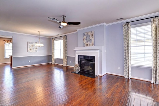 unfurnished living room featuring dark wood-type flooring, ceiling fan, crown molding, and a wealth of natural light