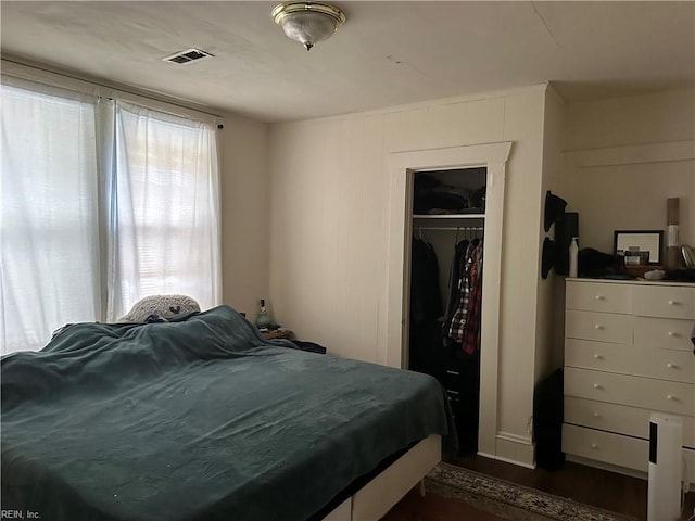 bedroom with dark hardwood / wood-style flooring and a closet