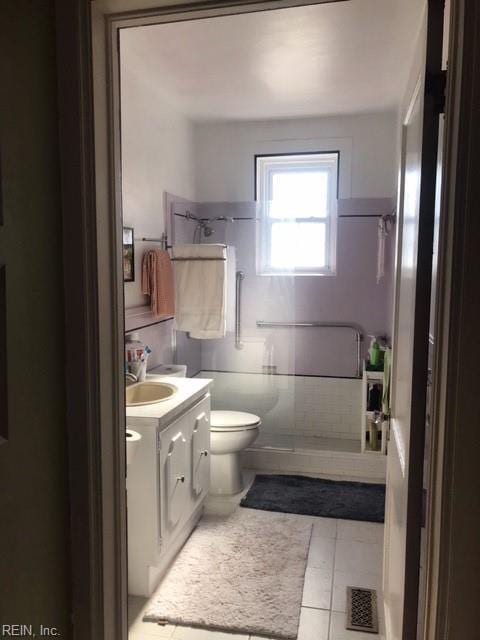 bathroom with vanity, toilet, tile patterned floors, and walk in shower