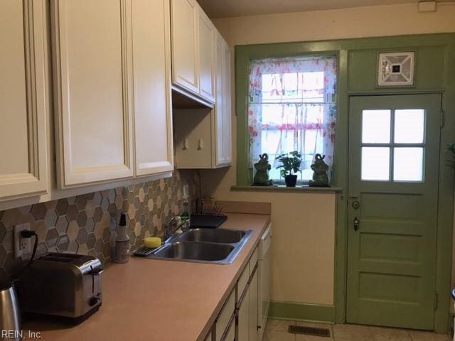 kitchen with white cabinetry, sink, decorative backsplash, and white dishwasher