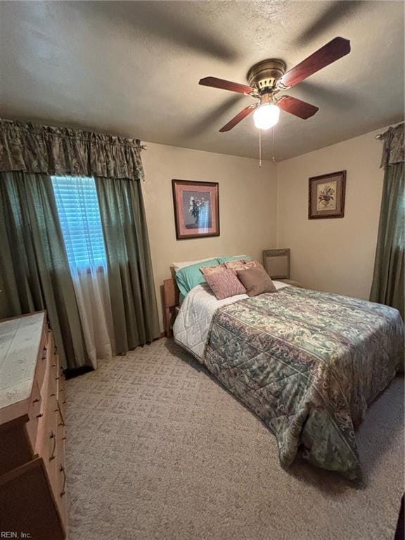 carpeted bedroom featuring ceiling fan and a textured ceiling