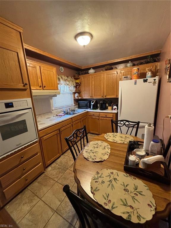 kitchen with ornamental molding, sink, light tile patterned floors, and white appliances