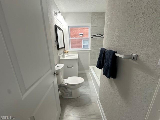 bathroom with vanity, tiled shower, a textured ceiling, and toilet