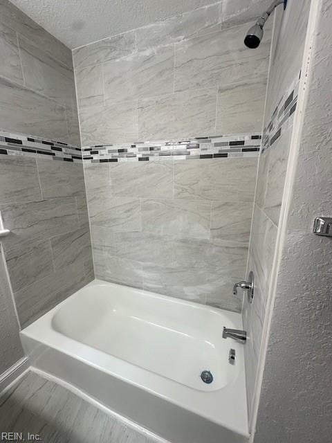 bathroom featuring tiled shower / bath combo and a textured ceiling