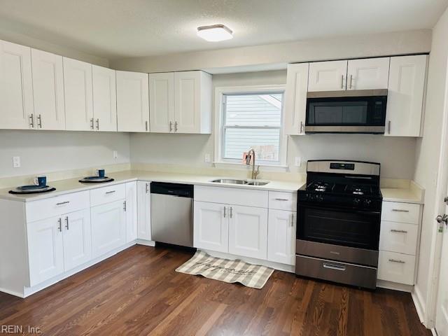 kitchen with dark hardwood / wood-style flooring, sink, stainless steel appliances, and white cabinets