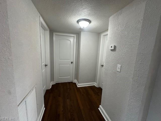 hallway featuring dark wood-type flooring and a textured ceiling