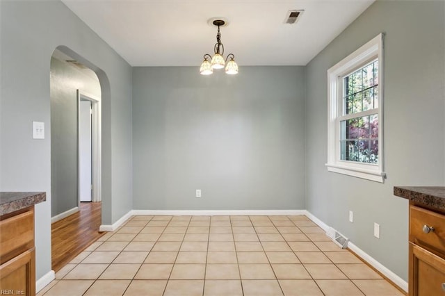 unfurnished dining area featuring a notable chandelier