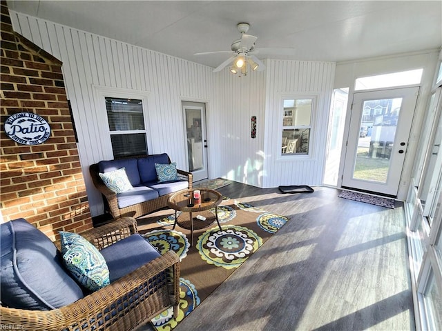 living room with hardwood / wood-style flooring, brick wall, and ceiling fan