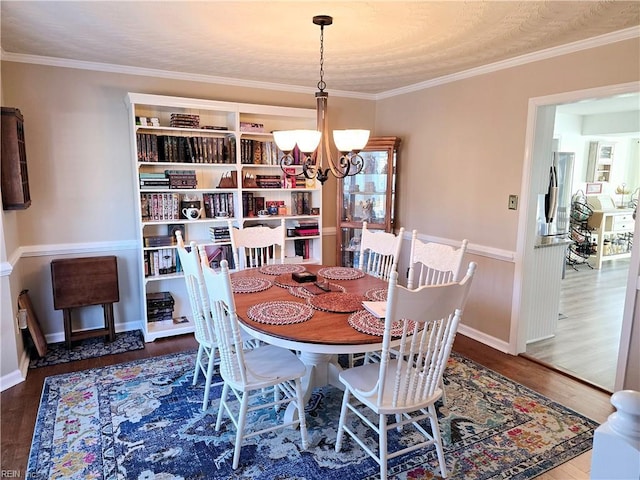 dining area featuring dark wood-type flooring, crown molding, and a notable chandelier