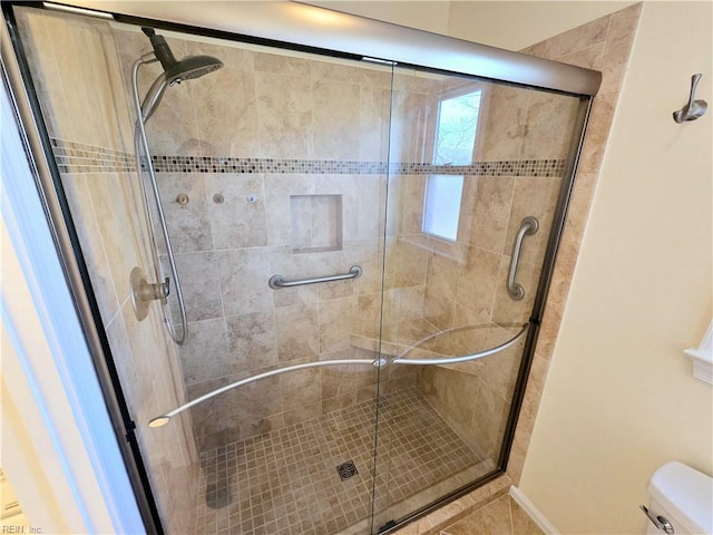 bathroom with a shower with shower door and toilet