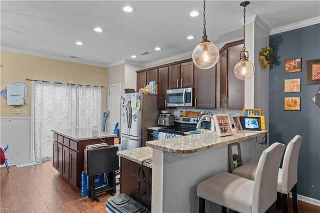 kitchen featuring appliances with stainless steel finishes, decorative light fixtures, dark brown cabinetry, kitchen peninsula, and light stone counters