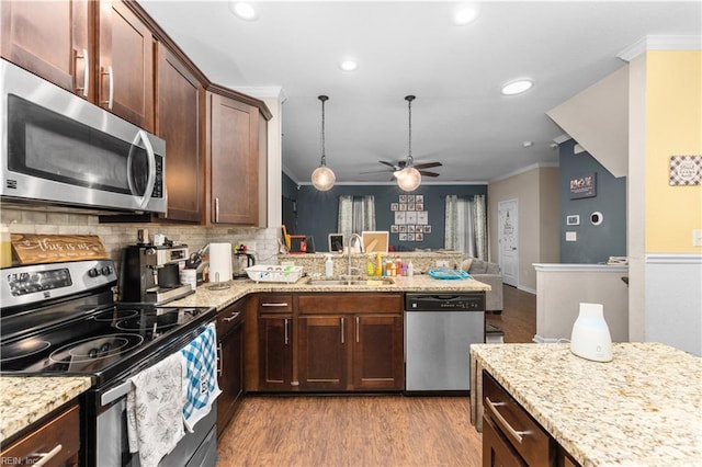 kitchen featuring sink, ornamental molding, kitchen peninsula, stainless steel appliances, and light wood-type flooring