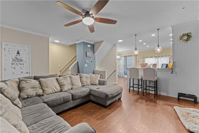 living room with wood-type flooring, ornamental molding, and ceiling fan