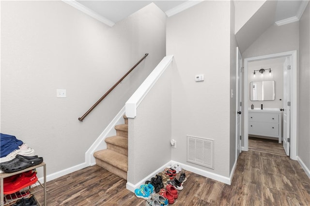 stairway with ornamental molding and hardwood / wood-style floors