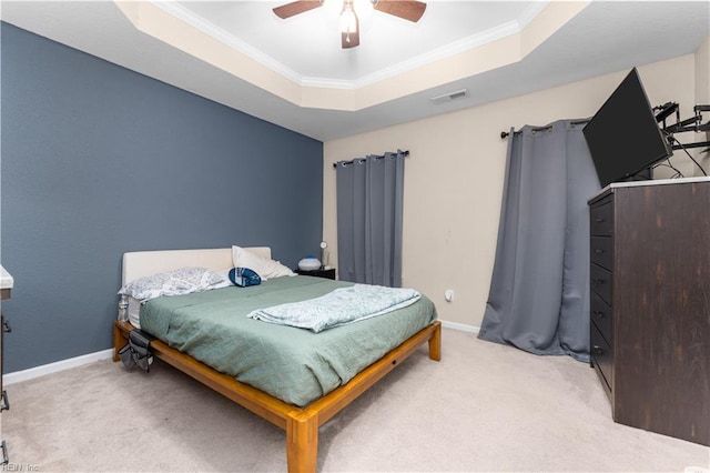 bedroom with crown molding, light colored carpet, a tray ceiling, and ceiling fan