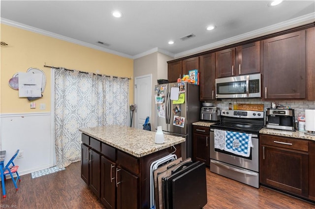 kitchen featuring stainless steel appliances, ornamental molding, dark wood-type flooring, and light stone counters