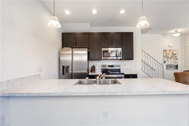 kitchen featuring hanging light fixtures, sink, stainless steel appliances, and kitchen peninsula