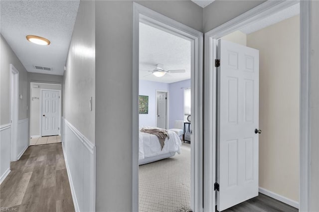 hallway with hardwood / wood-style flooring and a textured ceiling