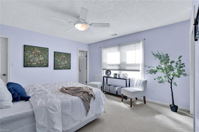 bedroom featuring light carpet, ceiling fan, and a textured ceiling