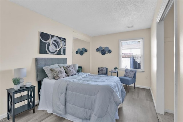 bedroom with a textured ceiling and light hardwood / wood-style flooring