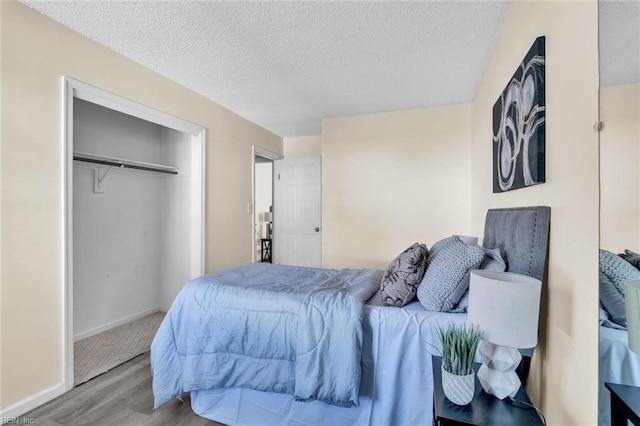 bedroom with a textured ceiling, light hardwood / wood-style floors, and a closet