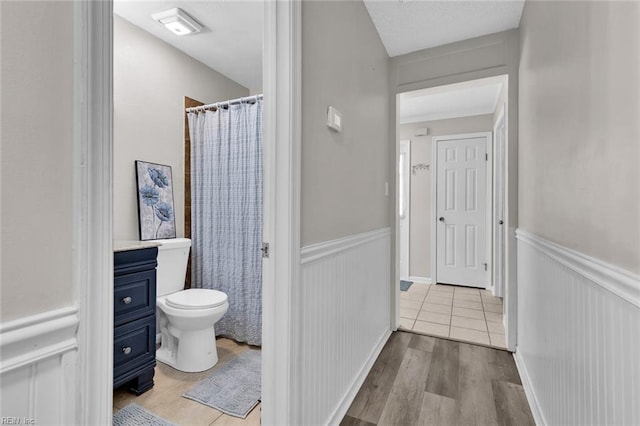 bathroom featuring wood-type flooring, toilet, a shower with shower curtain, and vanity