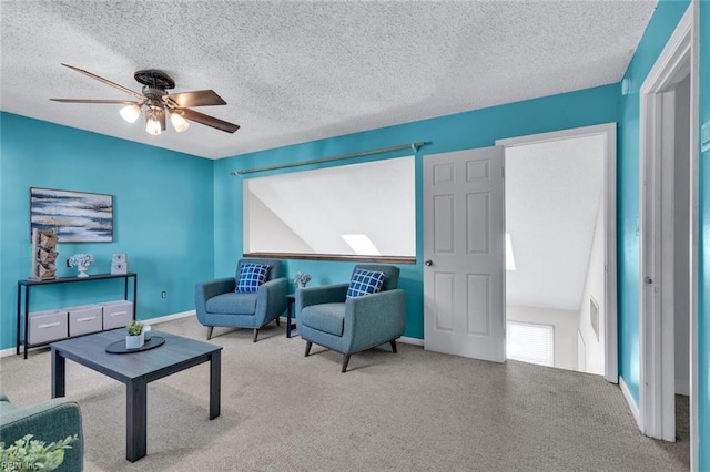 living area featuring ceiling fan, carpet floors, and a textured ceiling