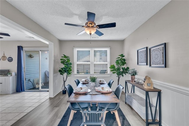 dining room with a textured ceiling, light hardwood / wood-style flooring, and ceiling fan