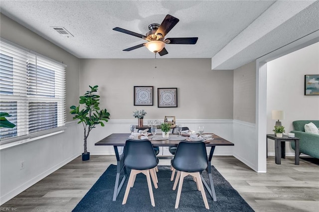 dining space with ceiling fan, light hardwood / wood-style flooring, and a textured ceiling