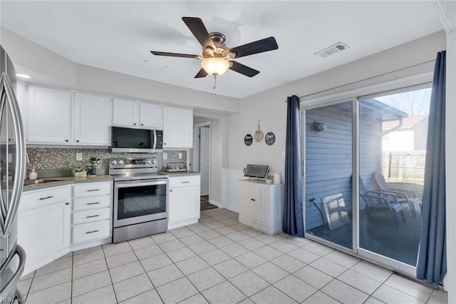 kitchen with stainless steel appliances, white cabinetry, light tile patterned flooring, and decorative backsplash