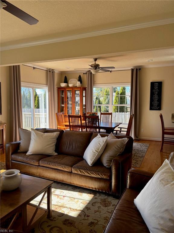 living room featuring ceiling fan, ornamental molding, wood-type flooring, and plenty of natural light